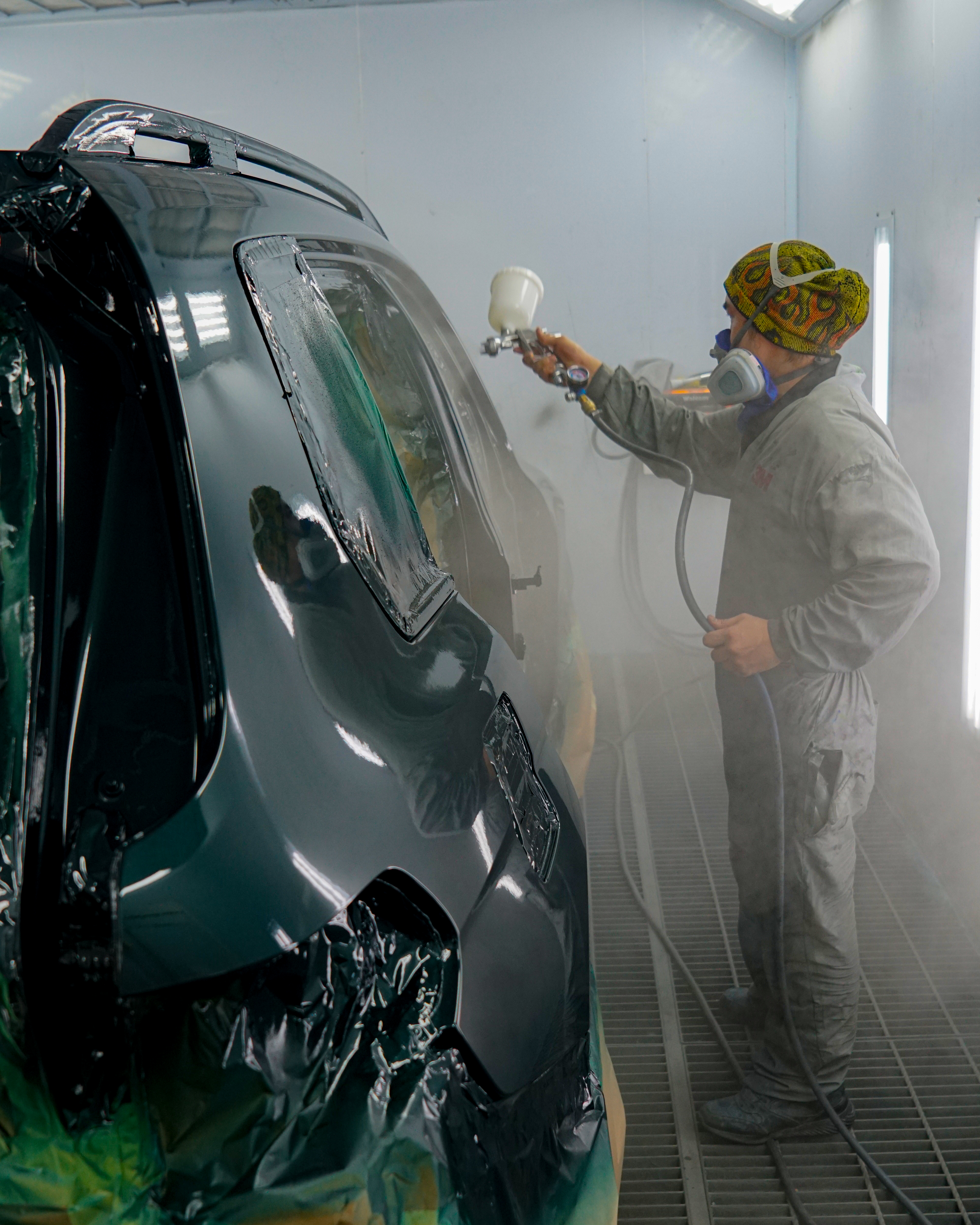A young male inspector in a black polo examining a car .Cardip