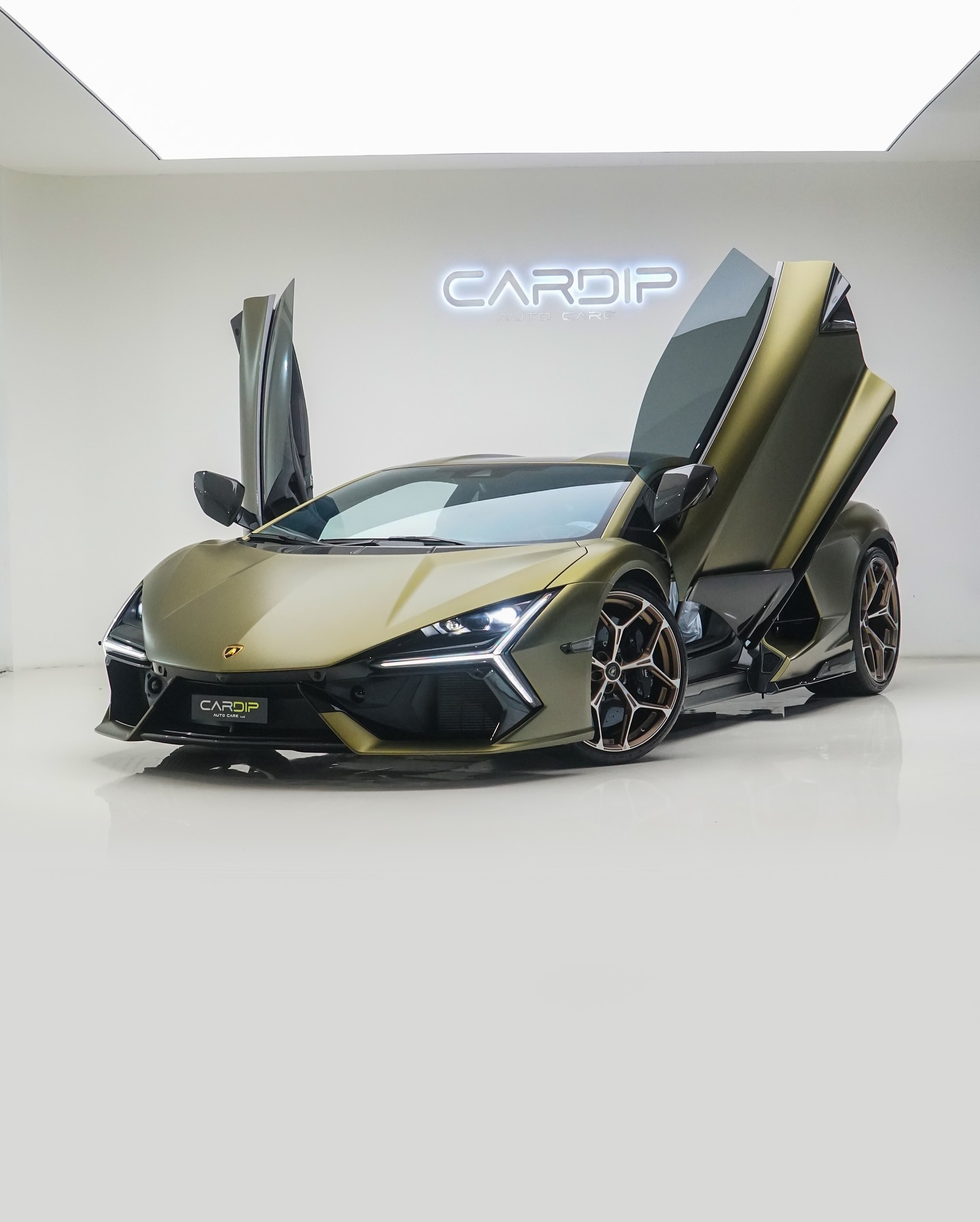 Lamborghini with a matte olive green vinyl wrap and butterfly doors open, showcased at the CarDip studio in Dubai.