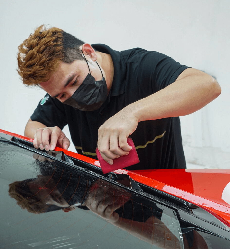 A person applying red PPF on the car