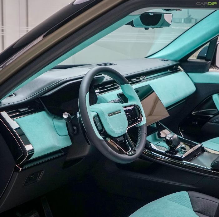 The interior of a luxury car featuring turquoise suede upholstery on the dashboard, steering wheel, doors, and seats, with glossy black trim and a modern touchscreen center console.